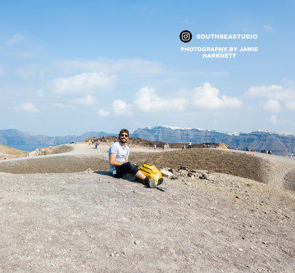 a man sitting on top of a mountain next to a body of water